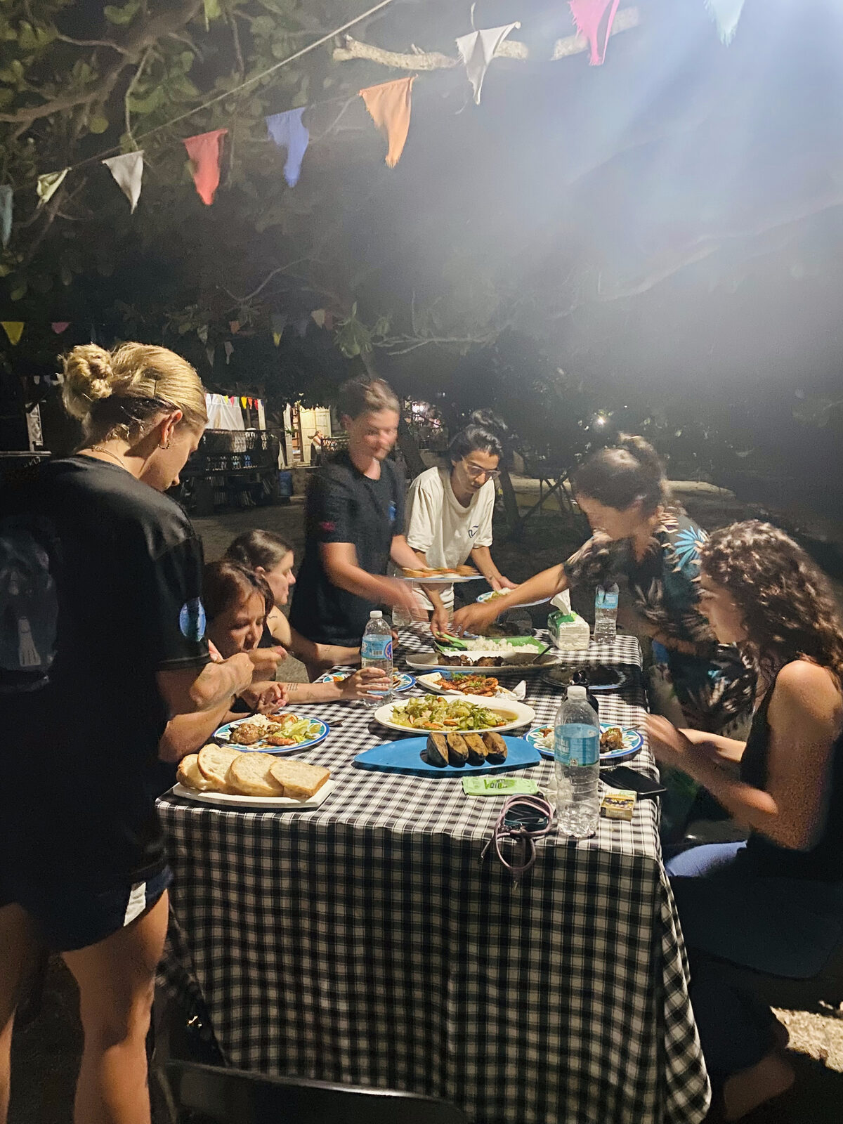 The group sharing an evening feast at a long table strung with festive bunting