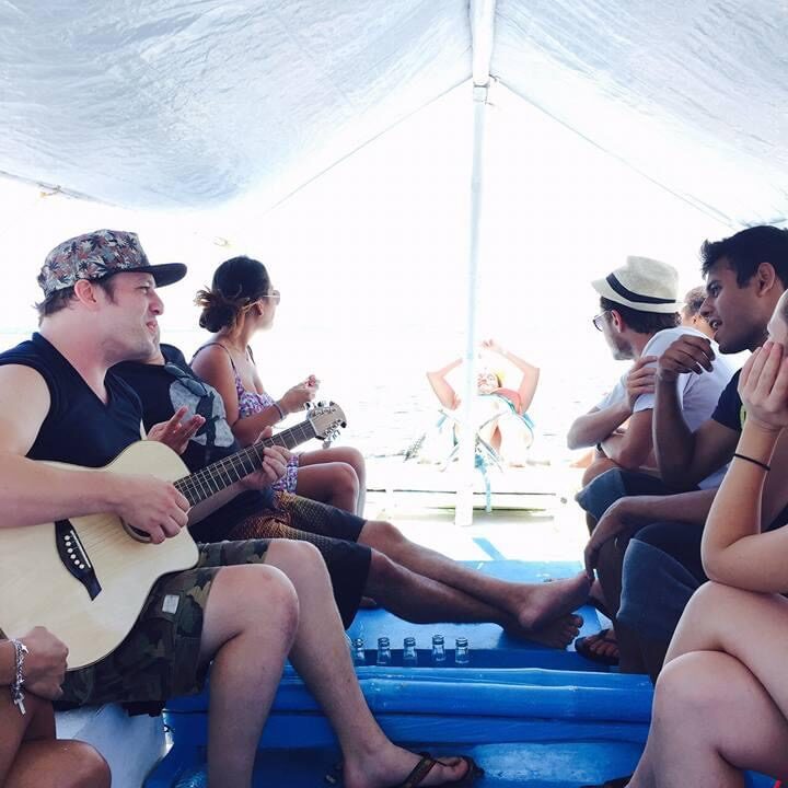 A guest playing guitar while the group relaxes on the boat