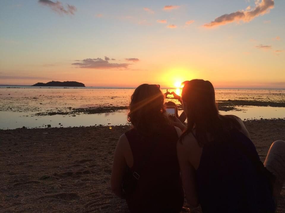 A couple taking a photo against the sunset on the beach