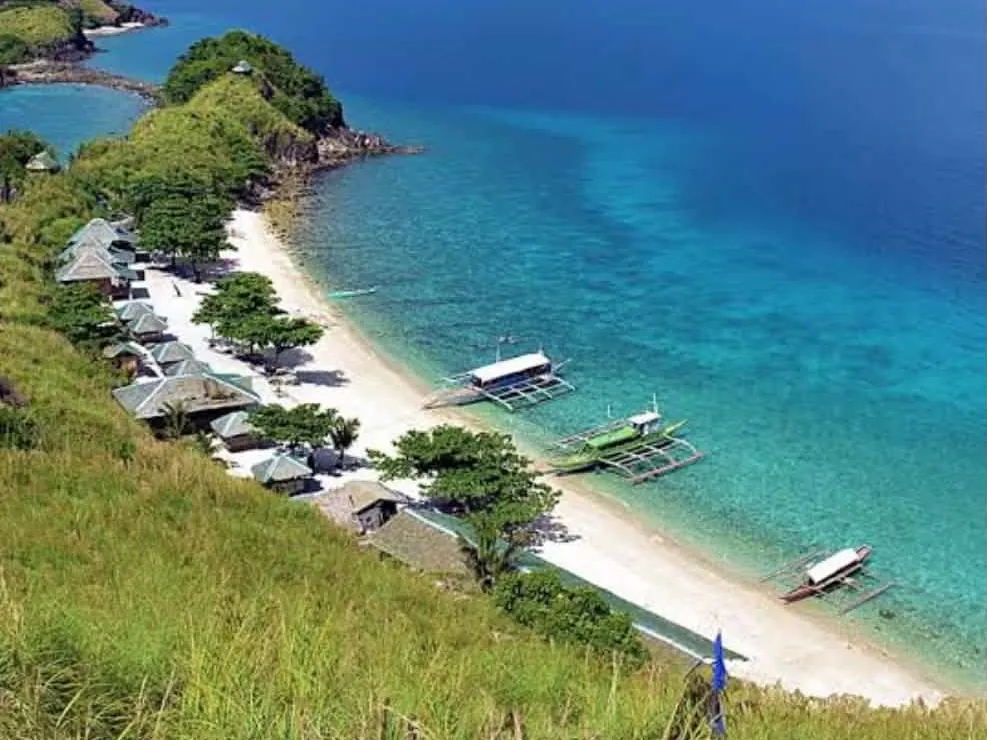 Aerial view of Sambawan Island's beachfront huts and outrigger boats along the white-sand shore