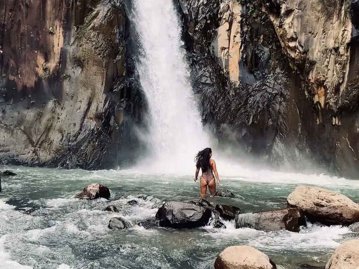 A guest wading through the river towards a canyon waterfall on Biliran Island