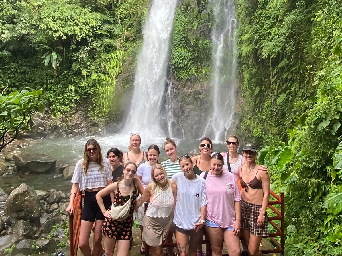 A large group of guests posing in front of twin waterfalls on Biliran Island