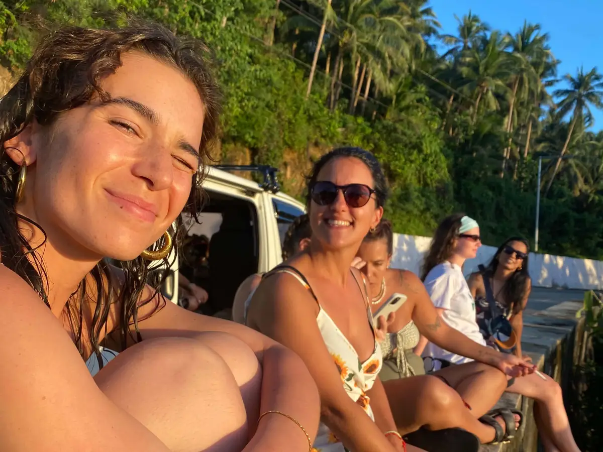 Guests relaxing on a wall beside the tour van at golden hour