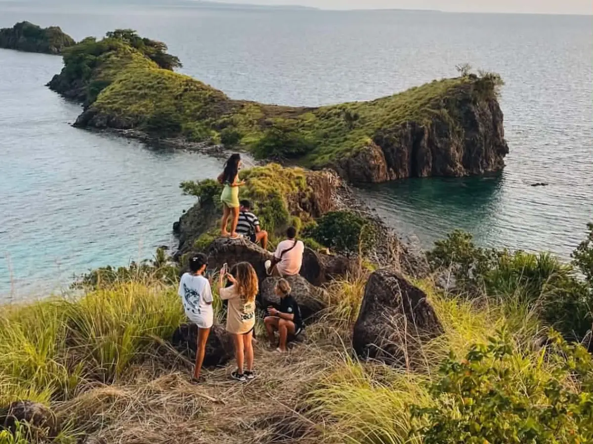 Guests on a grassy ridge looking out over the rocky headlands of Sambawan Island