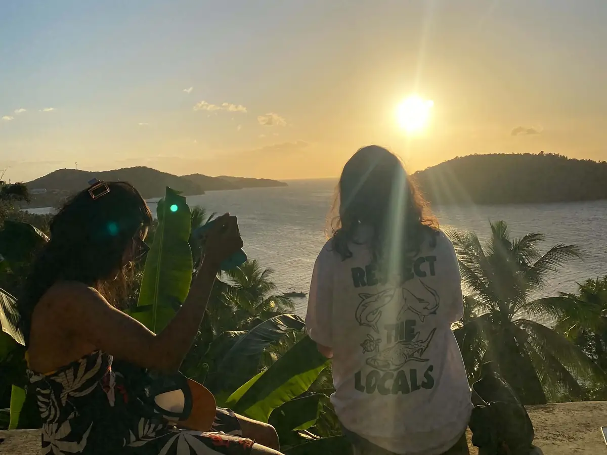 Two guests photographing the sunset from a viewpoint above the sea