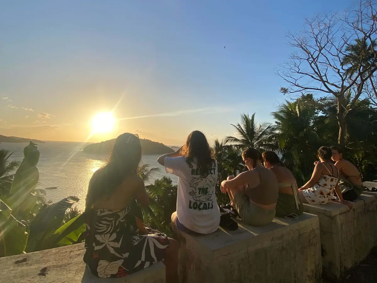 Guests watching the sunset from a hilltop wall overlooking the sea and a small island