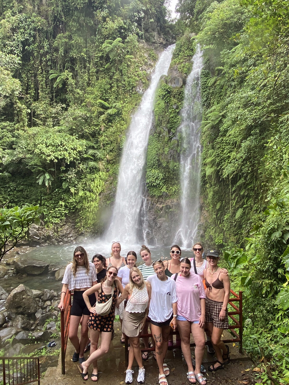 A group of guests at the foot of a jungle waterfall