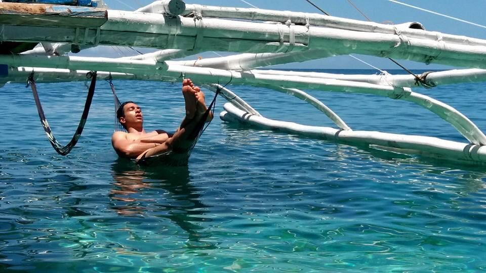 A guest holding on to the outrigger arm while swimming