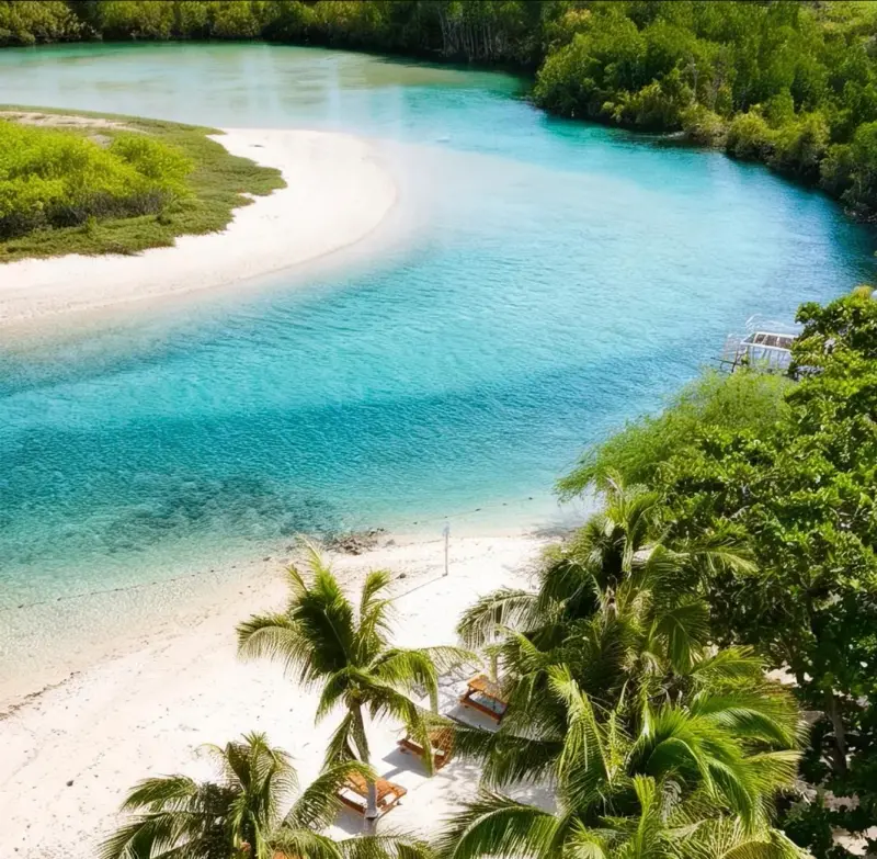 Aerial view of Balidbid Lagoon's turquoise inlet curving past white sand and coconut palms
