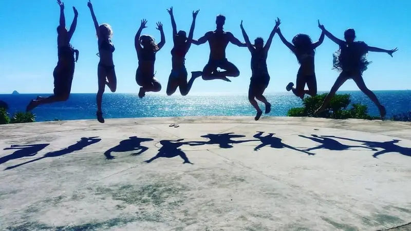 Group jumping in unison on rocks above a blue sea