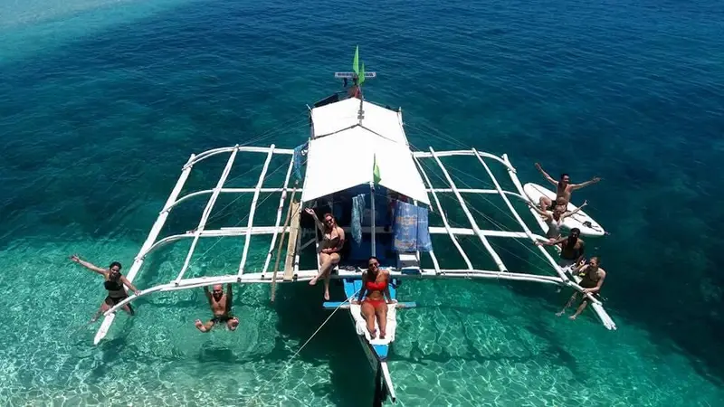 Aerial view of the outrigger boat over clear water at Carnaza