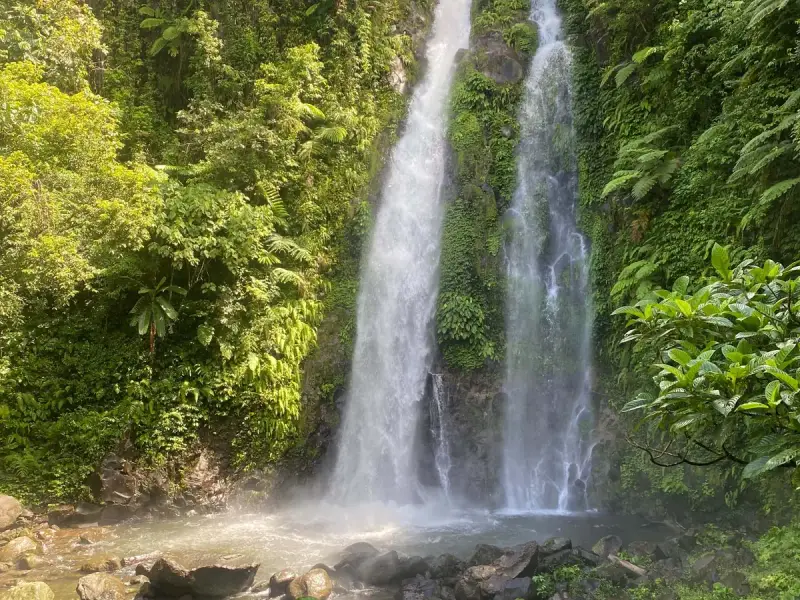 Twin waterfalls dropping through green jungle into a misty pool in Biliran, Leyte