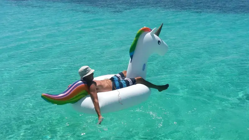 A guest floating on a unicorn inflatable in turquoise water
