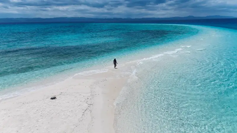 Aerial view of a guest walking along Kalanggaman's long white sandbar between turquoise shallows
