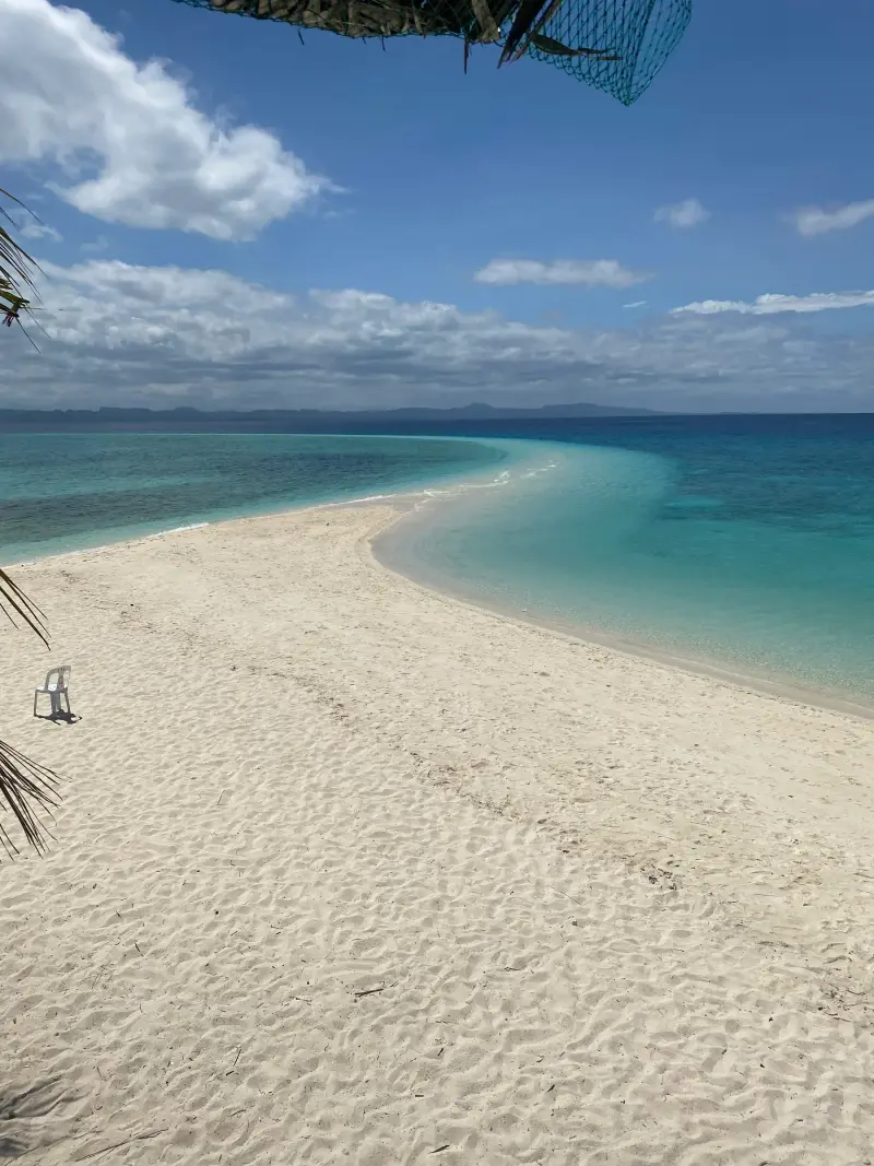Kalanggaman Island's white sandbar curving out into turquoise water under a blue sky, Palompon, Leyte