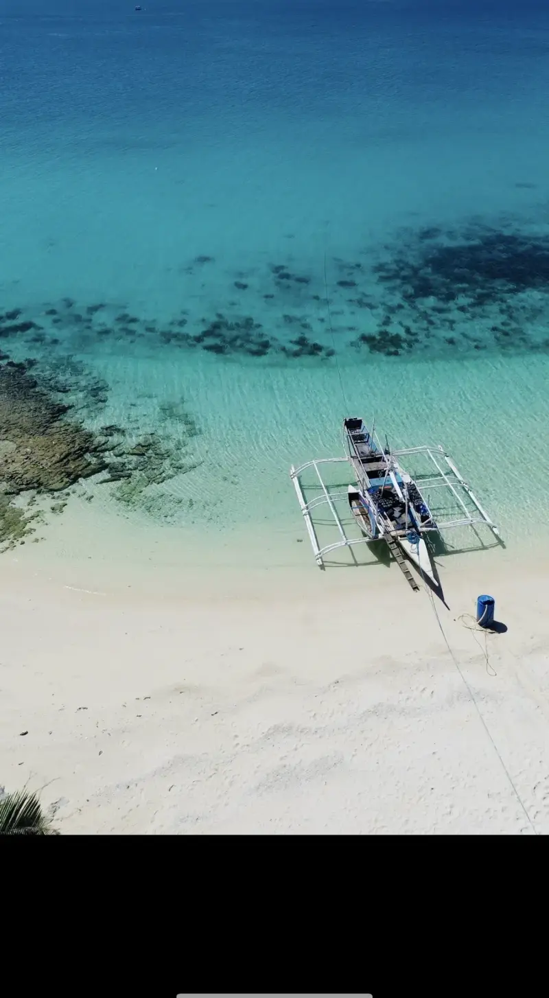 Aerial view of an outrigger bangka pulled up on the white sand at Virgin Island